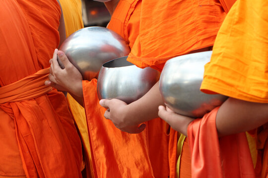 Buddhist monks holding alms bowls during morning alms giving in Thailand.