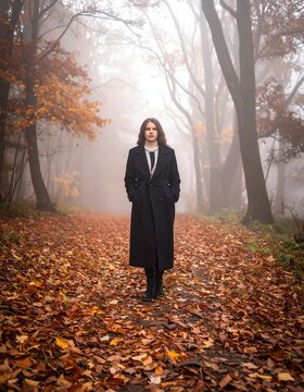 Woman in Black Coat Walking Through Misty Autumn Forest Path