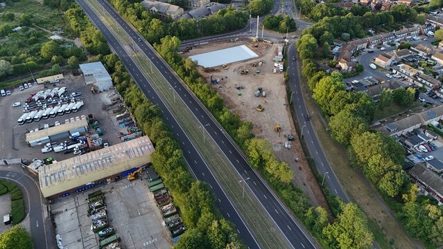 Aerial view of the construction site for a new supermarket car park featuring a concrete foundation and heavy machinery near the highway in Cheshunt, England, United Kingdom.