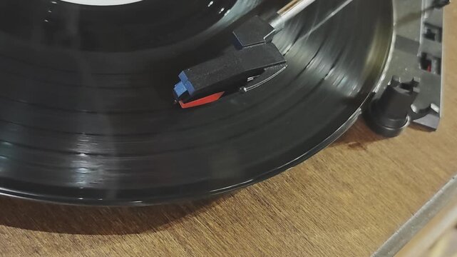 Nostalgic close up view of a spinning vinyl record. The player's stylus traces the grooves, evoking vintage audio and musical memories