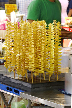Crispy golden Khoai Tay Chien Xoan Oc, or spiral tornado potato skewers, on display at street market.