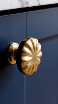 Ornate brass cabinet knob against a dark blue painted surface