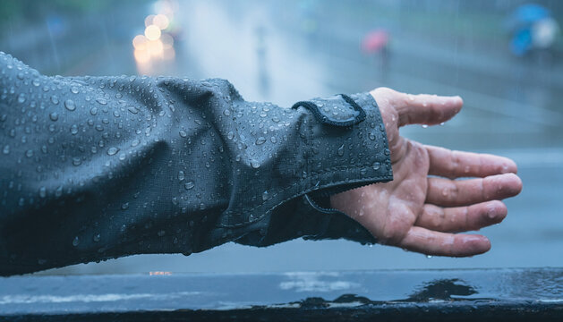 Hand Reaching Out in Rain with Water Droplets on Jacket