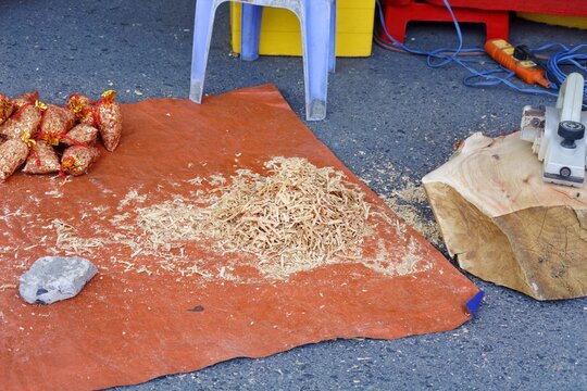 Fragrant go xa xi wood shavings piled on an orange tarp beside aromatic sachets and woodworking equipment.