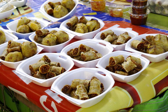 Delicious crispy cha gio and nem ran fried spring rolls displayed in bowls at a street food market.