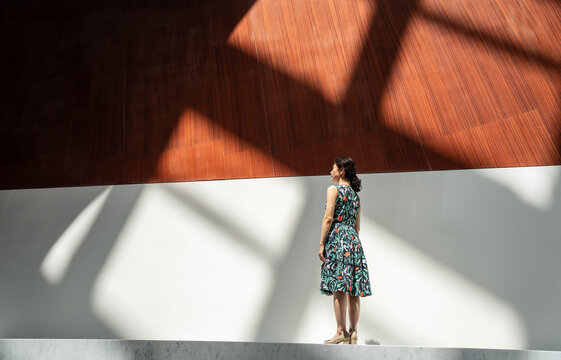 Woman Standing in Dramatic Sunlight in a Modern Architectural Interior