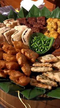 Vertical pan shot of traditional Indonesian fried snacks and gorengan platter served on banana leaf