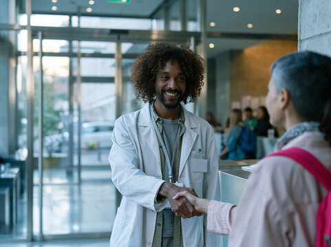 Smiling Doctor Shaking Hands with Patient in Hospital Reception