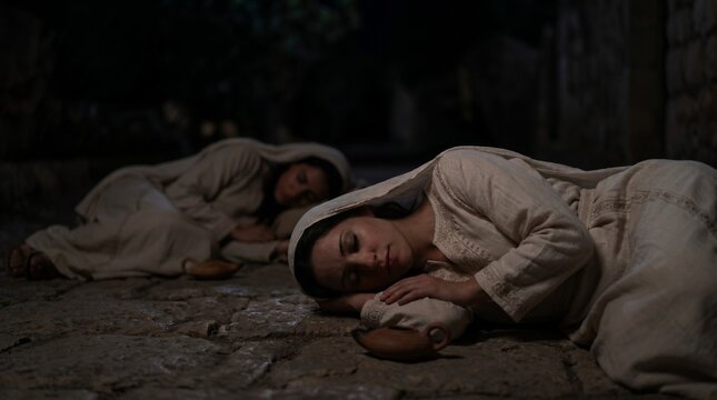Biblical bridesmaids from the parable 10 virgins sleeping on a stone floor in the dark
