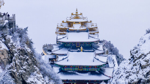 Snow-covered Golden Summit temples on Laojun Mountain in Henan, China, surrounded by dramatic winter mountain scenery.