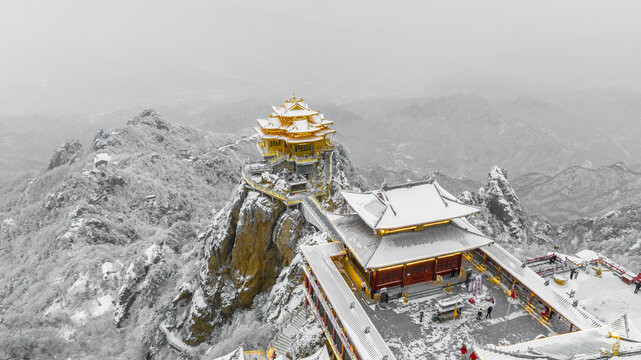 Snow-covered Golden Summit temples on Laojun Mountain in Henan, China, surrounded by dramatic winter mountain scenery.