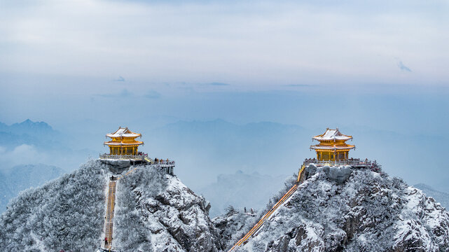 Snow-covered Golden Summit temples on Laojun Mountain in Henan, China, surrounded by dramatic winter mountain scenery.