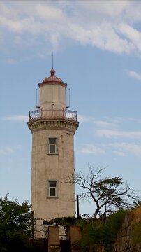 A lighthouse stands tall on the side of a hill, surrounded by trees