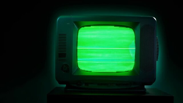 Retro vintage television with glowing green static screen in dark room nostalgic technology concept