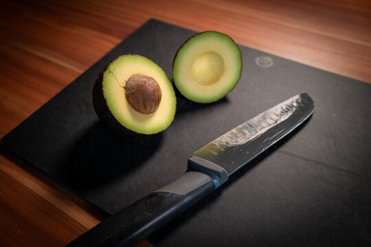 Halved Ripe Avocado Beside Chef Knife Close Up
