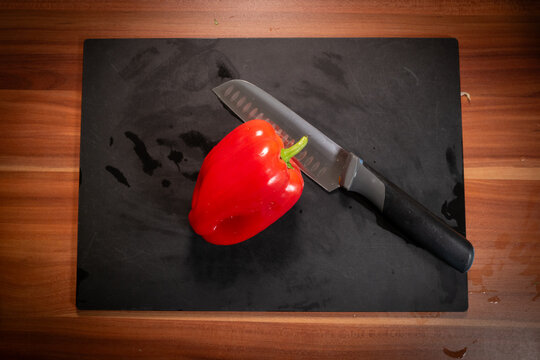 Whole Red Bell Pepper and Chef Knife on Cutting Board