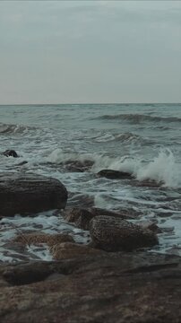 on a rocky beach next to the ocean, with waves crashing in the background