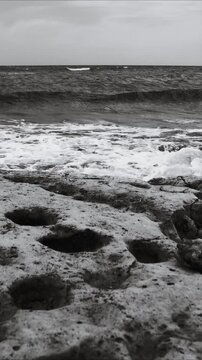 A black and white  of the ocean waves crashing against the shore
