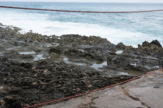 Jagged limestone shore and turquoise Caribbean water at Providencia Island in Providencia, Colombia