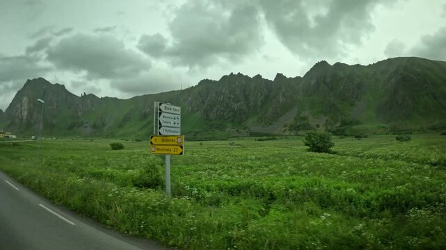 Driving past Bleik road sign intersection and jagged green mountains in Andoya Norway