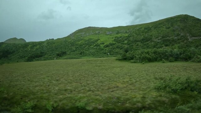 Driving past green arctic valley and peat bog hills in Andoya Norway