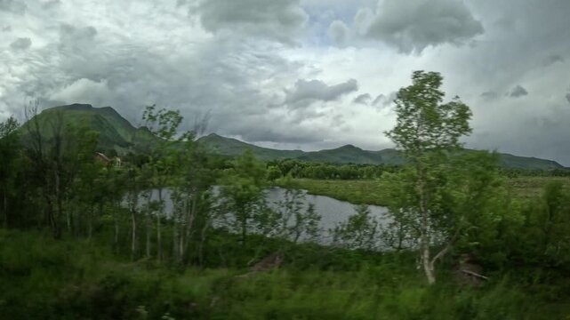 Driving past peat bog wetlands pond and red house in Andoya Norway