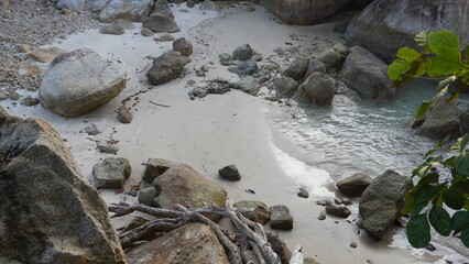 High angle view of big granite boulders surrounding a small white sand cove with sea water. © Ahmad