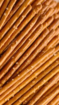 Salted Pretzel Sticks Texture. Macro view of golden brown pretzel sticks covered with coarse salt crystals. 