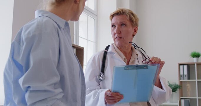Doctor consultation with patient reviewing results. A senior physician explains a diagnosis in a modern clinic, outlining options and next steps in treatment with empathy. Caring medical guidance.