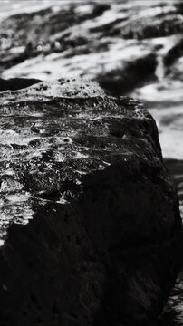 A black and white  of a rock partially submerged in calm water