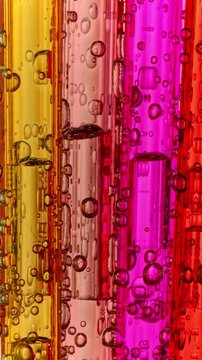 Colorful Liquid Bubbles in Transparent Tubes. Macro view of numerous air bubbles moving through red, orange and pink liquid inside parallel transparent tubes.