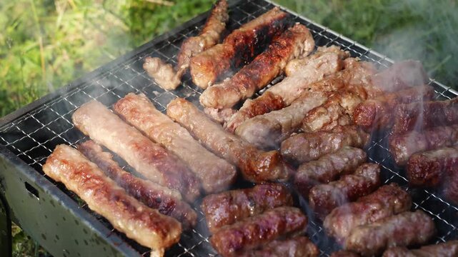 Tongs turn cevapi on a smoky charcoal grill during outdoor cooking. Traditional barbecue footage fits food, travel, summer and hospitality themes