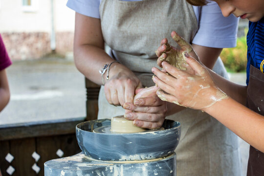 woman teaches teenager pottery, clay modeling, centering and pulling the walls of future pottery by hand, master, helps, shape, product, equipment, work surface, potter's wheel, work process, shapes p