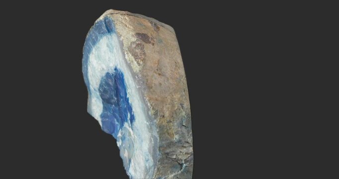 Close-up of a cut geode section showing blue and white concentric bands, a polished interior surface and contrasting rough natural exterior.