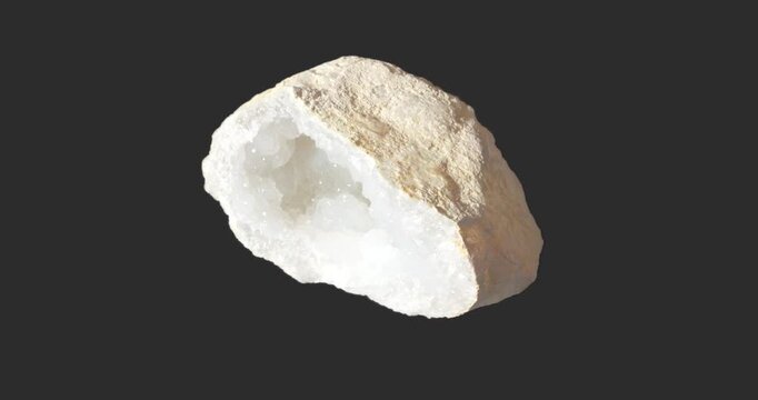 White crystal geode rotating on a dark gray background, revealing a deep sparkling crystalline cavity surrounded by a rough beige natural exterior.