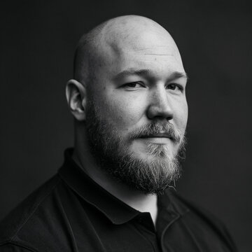 Studio portrait of a bald man with a beard looking seriously into the camera