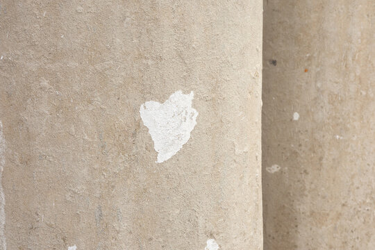 Beige concrete column texture, close-up of curved cement surface with white paint smear, rough architectural detail background.
