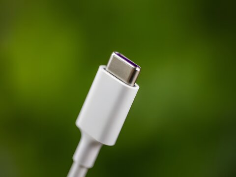 Close-up of USB-C cable connector plug isolated on blurred green background for tech devices