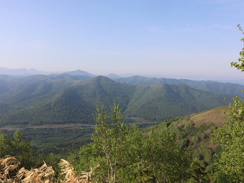 Green mountain ridges fading into summer haze under a blue sky