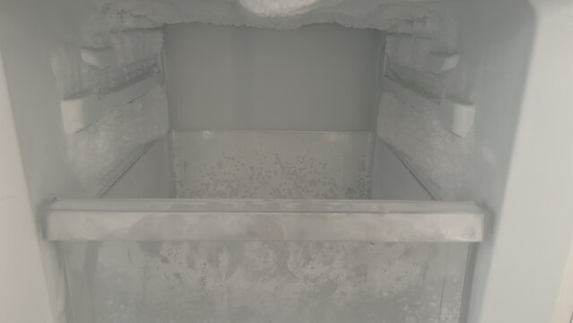 Empty freezer with frost buildup inside in kitchen at home