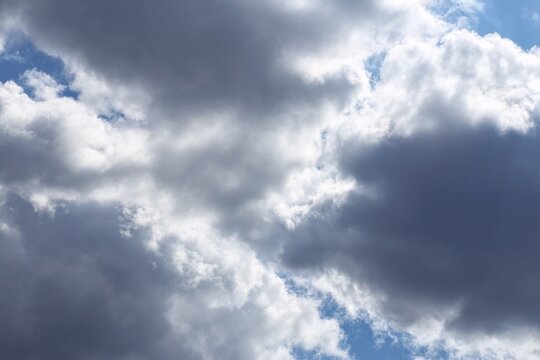 Dramatic storm clouds with sunlight breaking through overcast blue sky