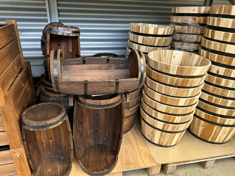 Wooden barrels and planters stacked at a location for sale