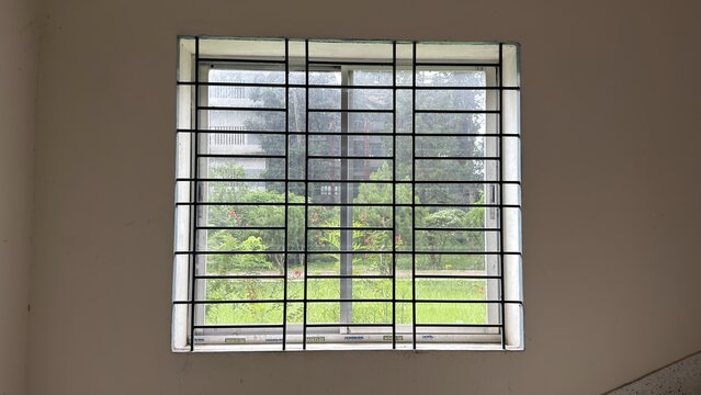 View through a barred window revealing lush green outdoor garden