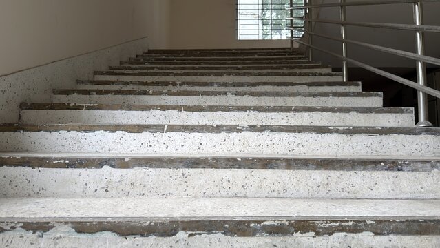 Concrete stairs with metal railing leading upwards towards a window