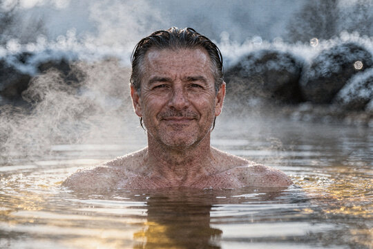 Man Relaxing Chest Deep in Steaming Hot Spring at Dawn