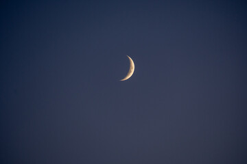 A crisp and clear waxing crescent moon stands out against a flawless deep blue sky. A perfect minimalist depiction of our serene celestial neighbor, ideal for backgrounds © AgioiDouloi
