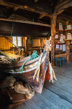 Historical wooden fishing vessel and dried stockfish inside a traditional maritime boathouse museum in the Lofoten islands in Norway.