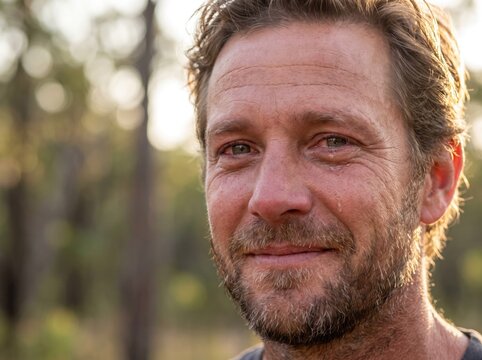 Portrait of a mature man smiling with emotional relief and peaceful expression outdoors.