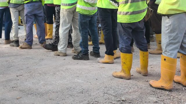 Construction Workers in Safety Boots Standing on Site Facing One Direction