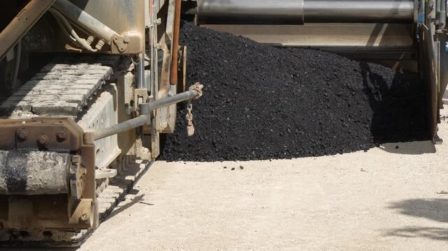 Industrial road construction asphalt paver crawler track and material hopper operating on highway subbase paving site operations